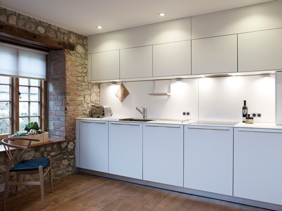 Small rustic enclosed kitchen in Devon with flat-panel cabinets, white cabinets and white splashback.