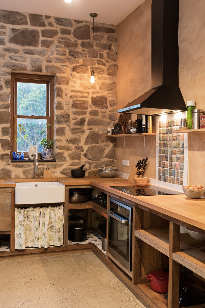 Foto de cocina de estilo de casa de campo con armarios abiertos, encimera de madera y suelo de cemento