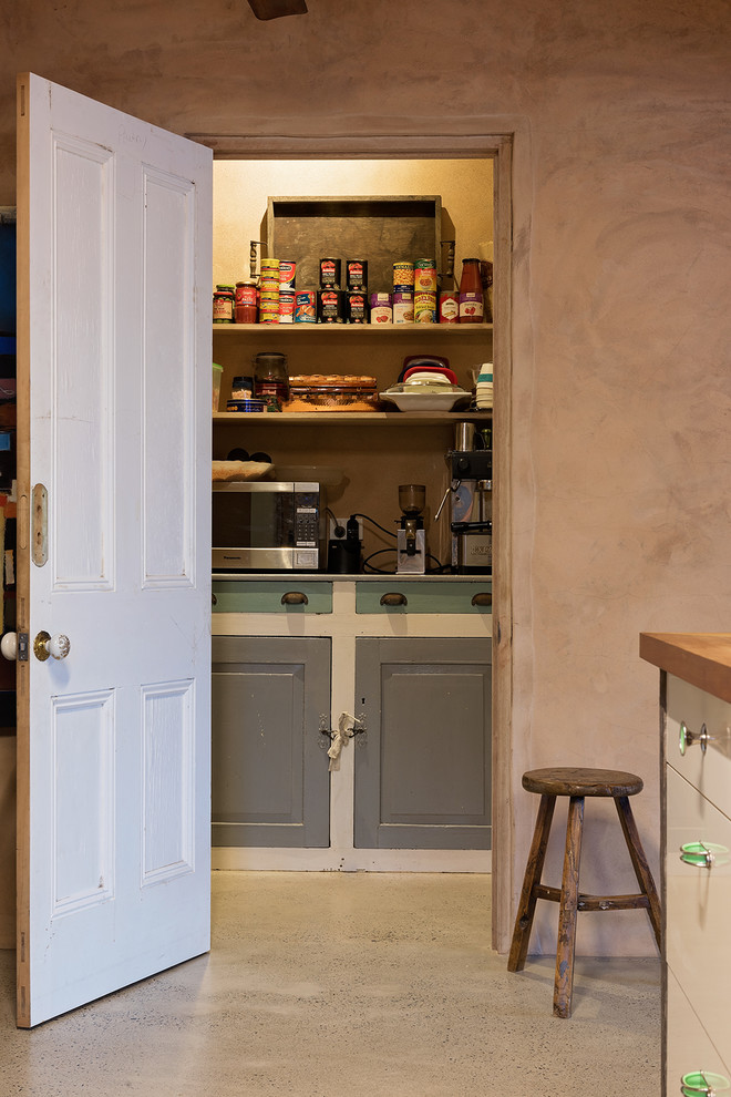 Aménagement d'une cuisine campagne avec un placard sans porte, un plan de travail en bois et sol en béton ciré.