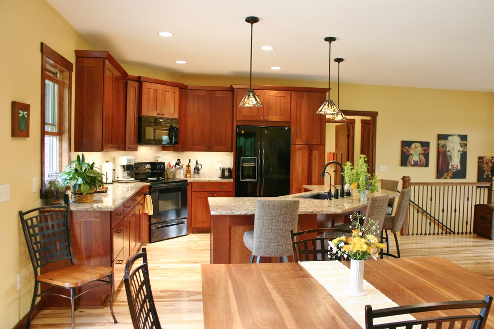 Foto på ett mellanstort amerikanskt kök, med en undermonterad diskho, skåp i shakerstil, skåp i mellenmörkt trä, bänkskiva i kvarts, beige stänkskydd, stänkskydd i stenkakel, svarta vitvaror, ljust trägolv och en köksö