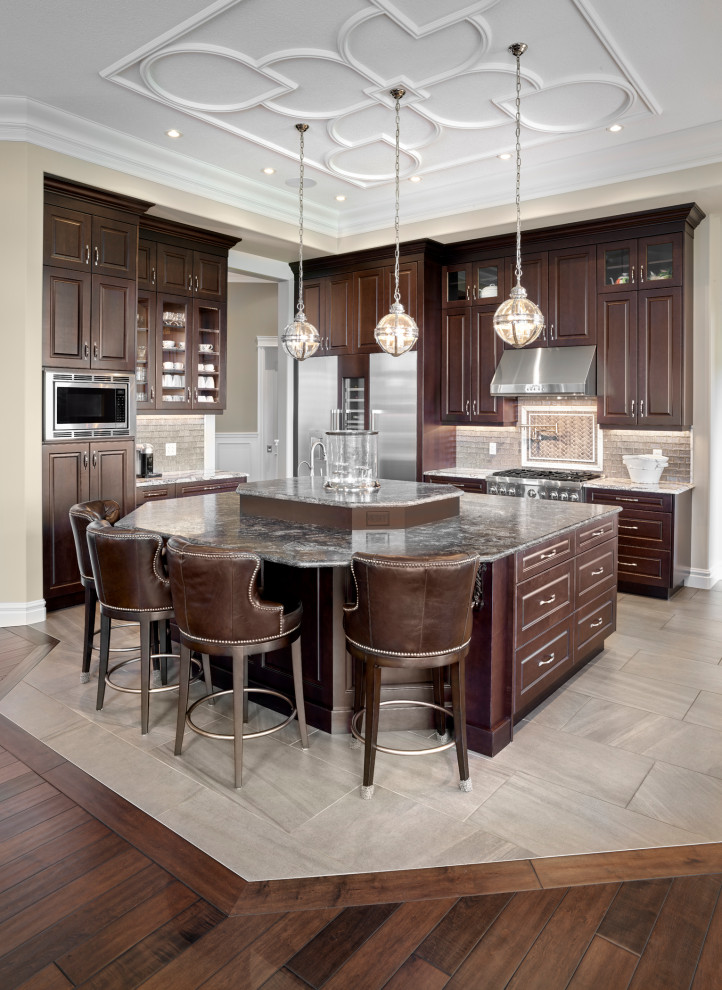 Eat-in kitchen - large traditional u-shaped porcelain tile and beige floor eat-in kitchen idea in Edmonton with an undermount sink, raised-panel cabinets, dark wood cabinets, granite countertops, metallic backsplash, ceramic backsplash, stainless steel appliances, an island and gray countertops