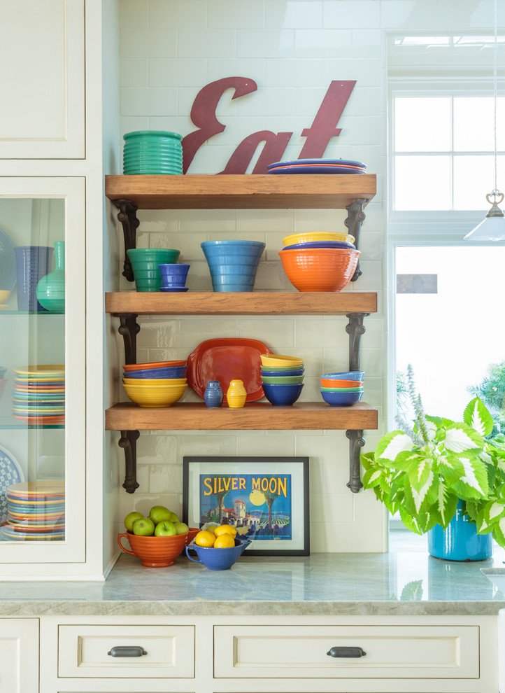 Example of a large beach style light wood floor and brown floor open concept kitchen design in Los Angeles with a farmhouse sink, shaker cabinets, white cabinets, quartzite countertops, white backsplash, ceramic backsplash, stainless steel appliances and an island