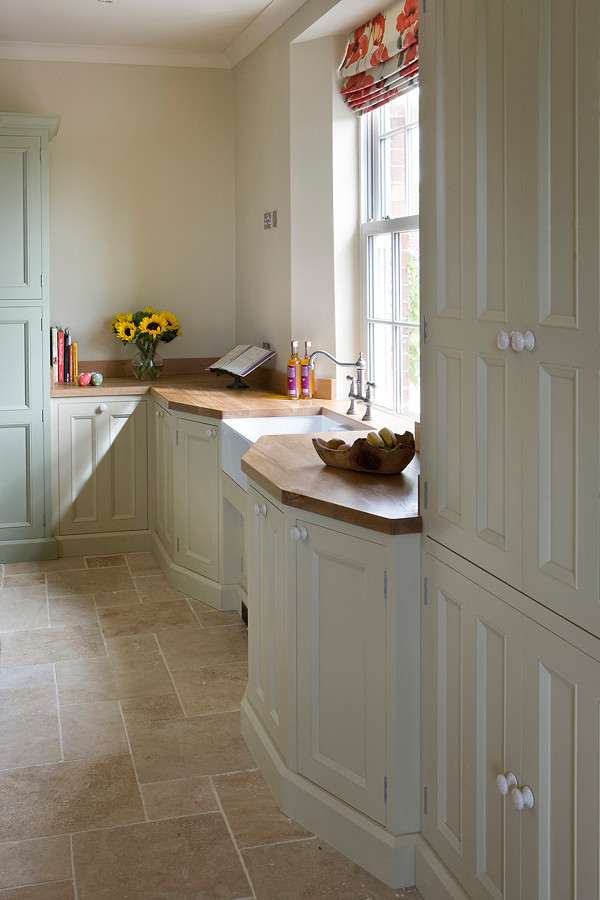 Country kitchen in Other with beaded cabinets and wood worktops.