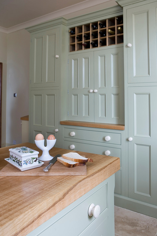 Farmhouse kitchen in Other with beaded cabinets and wood worktops.