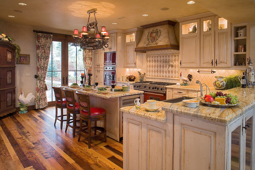Foto på ett mellanstort vintage flerfärgad kök, med luckor med upphöjd panel, skåp i slitet trä, granitbänkskiva, beige stänkskydd, stänkskydd i stenkakel, en rustik diskho, rostfria vitvaror, mellanmörkt trägolv och flera köksöar