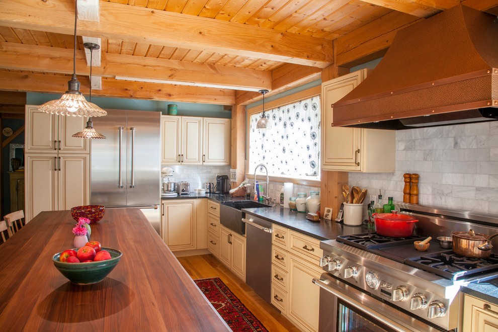 Idéer för att renovera ett stort lantligt kök och matrum, med en rustik diskho, luckor med upphöjd panel, beige skåp, bänkskiva i täljsten, vitt stänkskydd, stänkskydd i stenkakel, rostfria vitvaror, mellanmörkt trägolv och en köksö