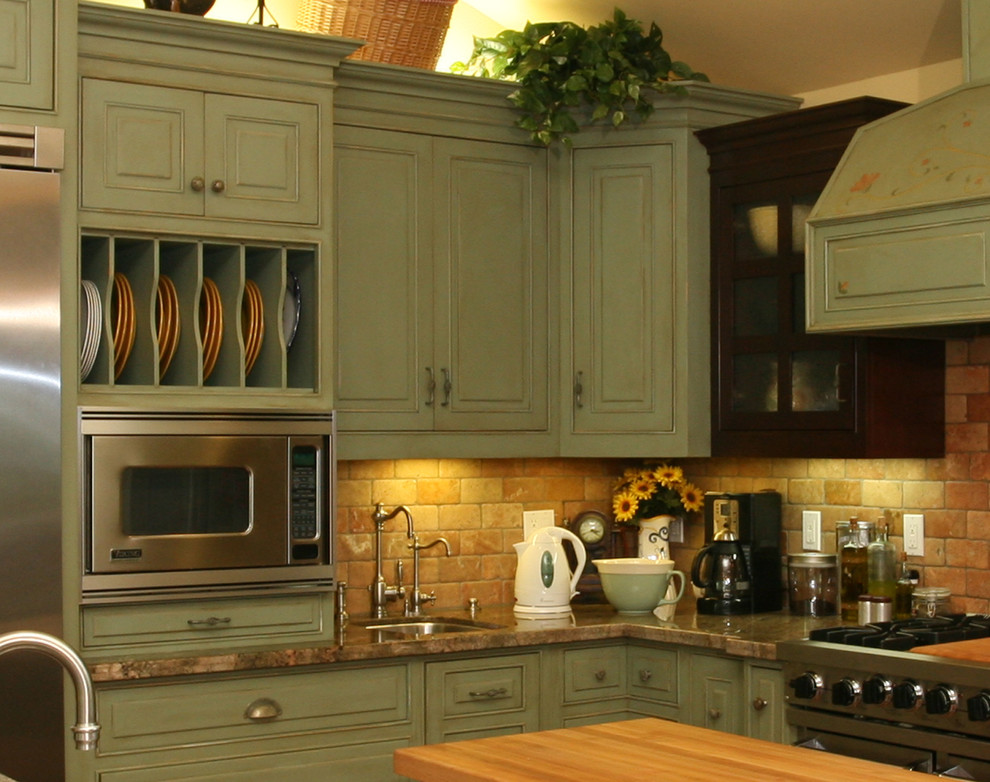Idéer för att renovera ett stort lantligt kök, med en rustik diskho, luckor med upphöjd panel, gröna skåp, granitbänkskiva, orange stänkskydd, stänkskydd i tunnelbanekakel, rostfria vitvaror, klinkergolv i keramik och en köksö