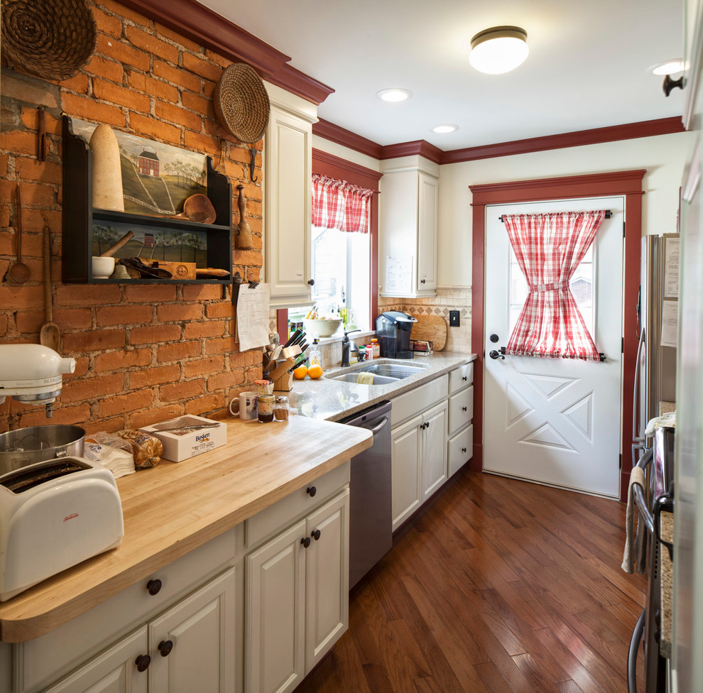 Zweizeilige, Kleine Country Küche ohne Insel mit Unterbauwaschbecken, profilierten Schrankfronten, weißen Schränken, Küchengeräten aus Edelstahl und braunem Holzboden in Cincinnati