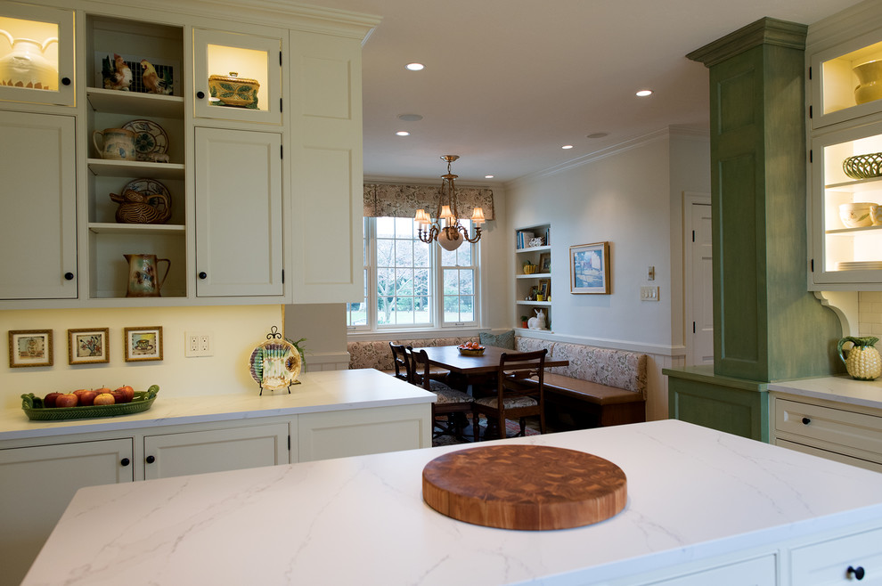 Example of a mid-sized classic u-shaped limestone floor and beige floor eat-in kitchen design in Philadelphia with a farmhouse sink, beaded inset cabinets, white cabinets, quartz countertops, white backsplash, subway tile backsplash, paneled appliances, an island and white countertops