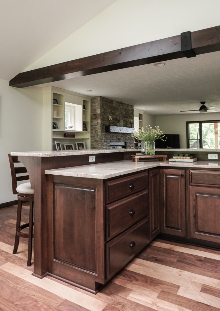 Large transitional l-shaped medium tone wood floor and brown floor eat-in kitchen photo in Columbus with an undermount sink, raised-panel cabinets, dark wood cabinets, granite countertops, beige backsplash, travertine backsplash, stainless steel appliances, two islands and brown countertops