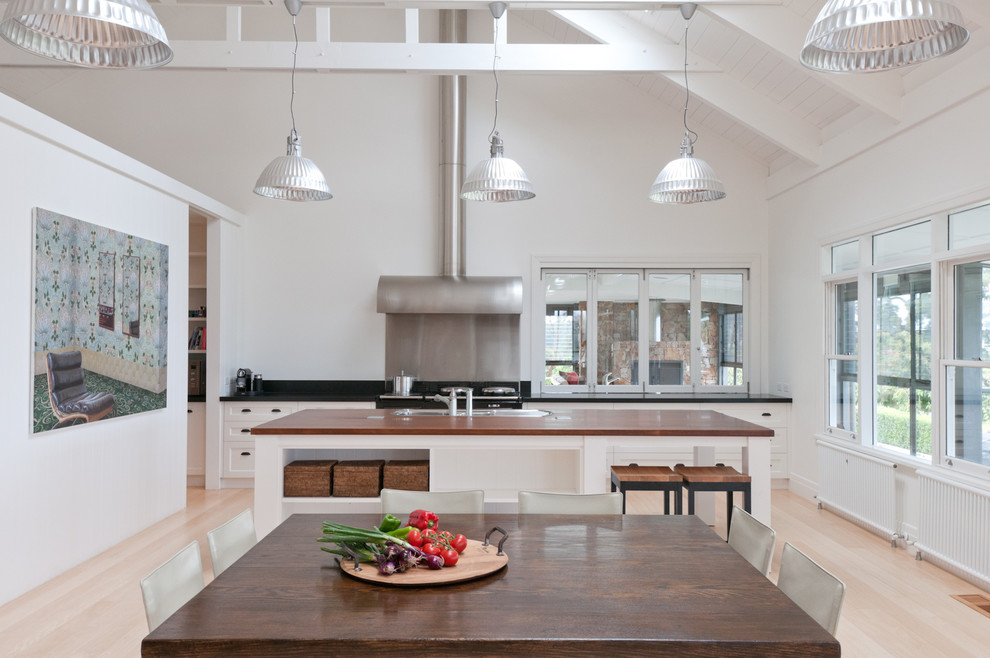 Moderne Wohnküche mit weißen Schränken und hellem Holzboden in Melbourne