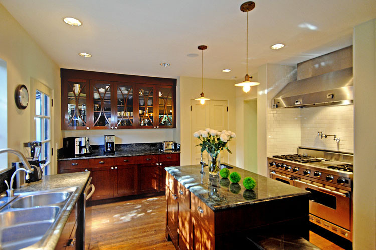 Example of a trendy kitchen design in Toronto with a triple-bowl sink, shaker cabinets, dark wood cabinets and stainless steel appliances