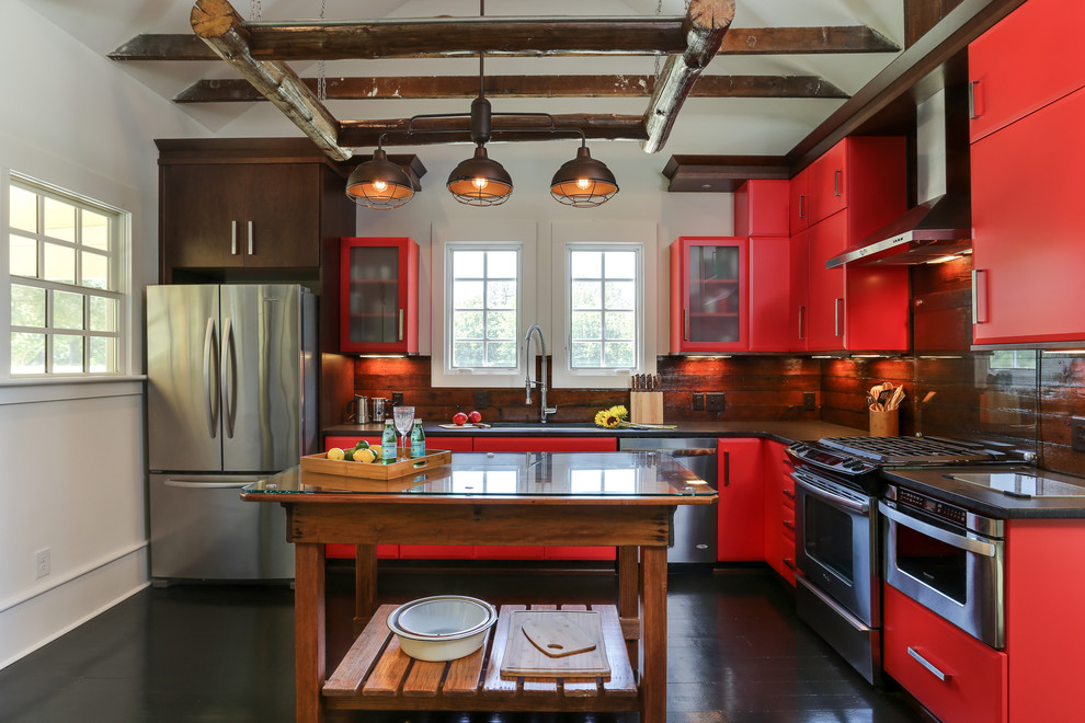 На фото: угловая кухня в стиле рустика с плоскими фасадами, красными фасадами, коричневым фартуком, техникой из нержавеющей стали, деревянным полом и островом