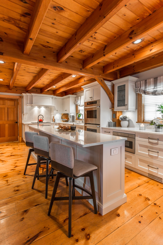 Foto di una cucina stile rurale con ante in stile shaker, ante bianche, elettrodomestici in acciaio inossidabile, pavimento in legno massello medio e top grigio