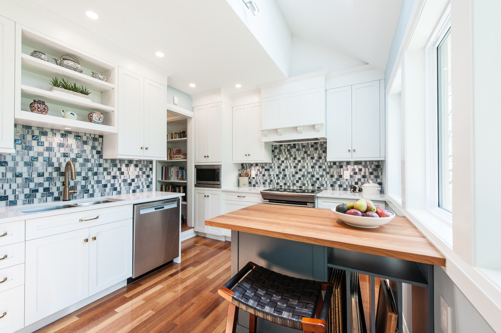 Inspiration for a small transitional u-shaped medium tone wood floor and orange floor enclosed kitchen remodel in Ottawa with an undermount sink, shaker cabinets, white cabinets, quartz countertops, blue backsplash, mosaic tile backsplash, stainless steel appliances and an island