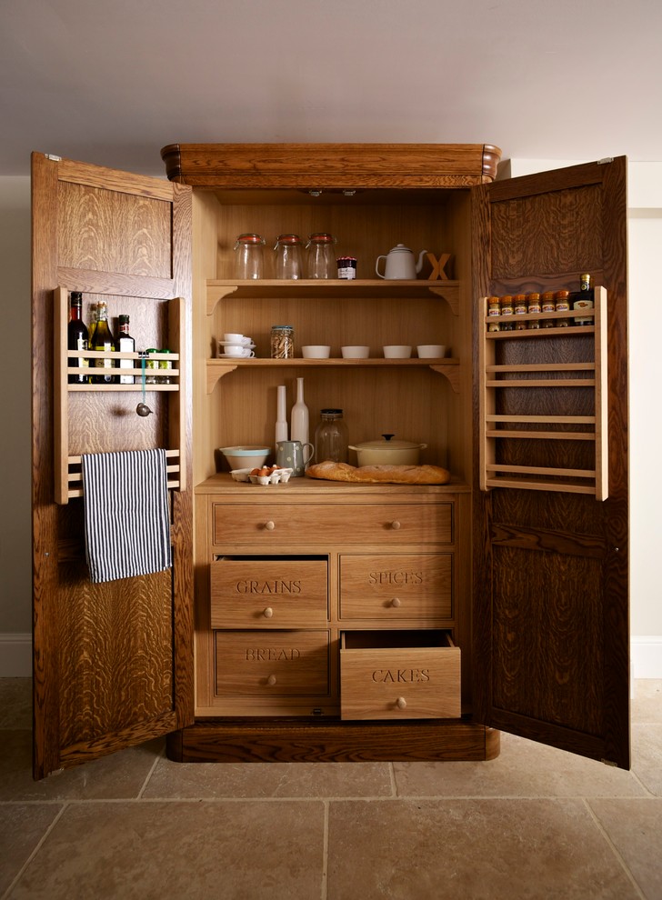 This is an example of a medium sized country l-shaped kitchen pantry in Essex with a submerged sink, flat-panel cabinets, medium wood cabinets, wood worktops, multi-coloured splashback, ceramic splashback, black appliances, travertine flooring and an island.