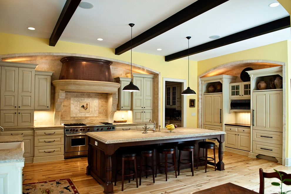 ワシントンD.C.にあるトラディショナルスタイルのおしゃれなコの字型キッチン (レイズドパネル扉のキャビネット、ベージュのキャビネット、パネルと同色の調理設備) の写真