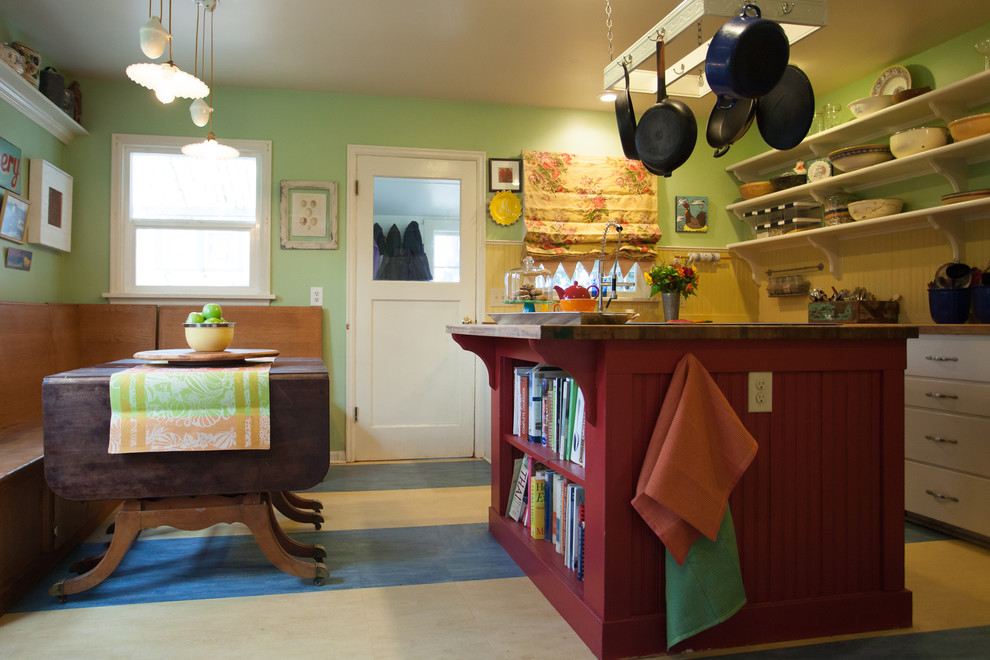 シアトルにある低価格の中くらいなカントリー風のおしゃれなキッチン (エプロンフロントシンク、フラットパネル扉のキャビネット、白いキャビネット、木材カウンター、ベージュキッチンパネル、木材のキッチンパネル、シルバーの調理設備、クッションフロア、マルチカラーの床、茶色いキッチンカウンター) の写真