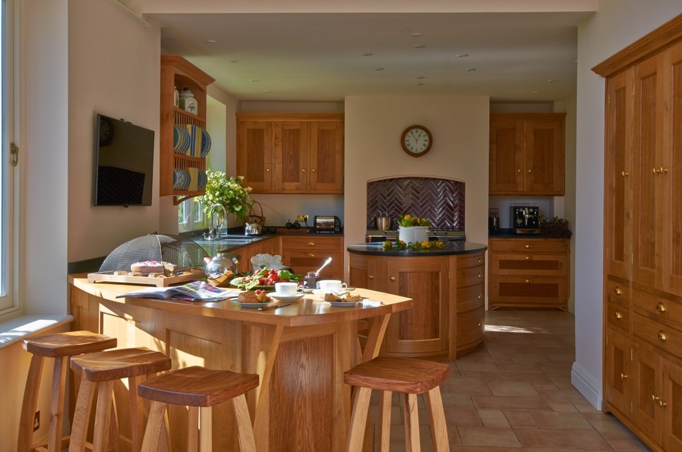 Aménagement d'une grande cuisine américaine classique en bois brun avec îlot, un placard avec porte à panneau encastré et un plan de travail en granite.