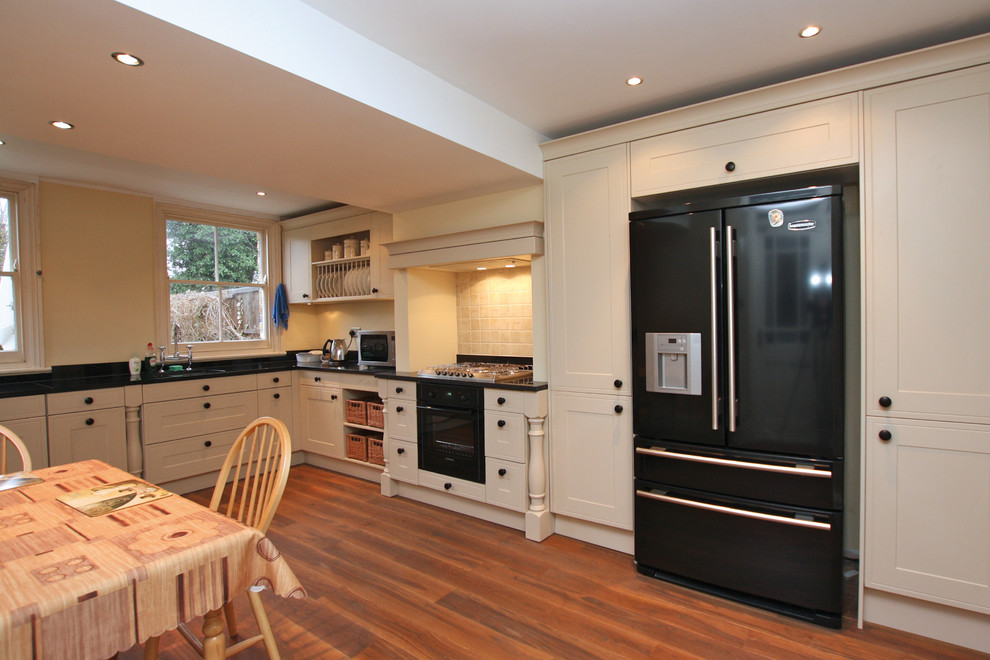 Diseño de cocina campestre con puertas de armario beige, suelo de madera en tonos medios y encimera de granito