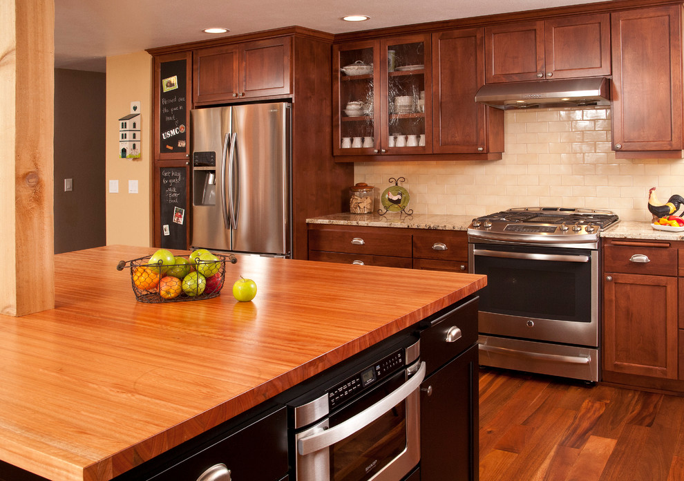 Eat-in kitchen - mid-sized traditional l-shaped medium tone wood floor eat-in kitchen idea in Seattle with an undermount sink, shaker cabinets, medium tone wood cabinets, wood countertops, beige backsplash, subway tile backsplash, stainless steel appliances and an island