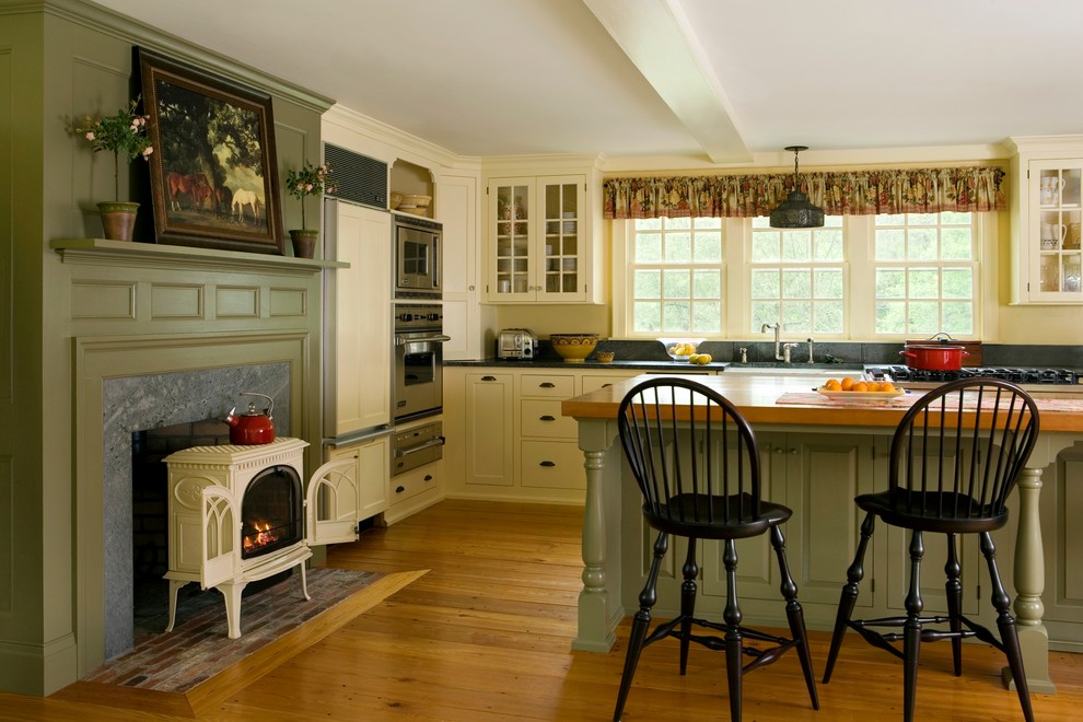 Idéer för mellanstora lantliga kök, med mellanmörkt trägolv, en köksö, luckor med infälld panel, en rustik diskho, gröna skåp och rostfria vitvaror