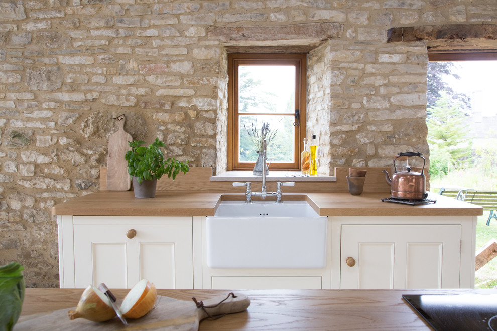 Photo of a large rural u-shaped open plan kitchen in Other with a belfast sink, white cabinets, wood worktops, ceramic flooring, an island, beaded cabinets, stainless steel appliances and brown worktops.