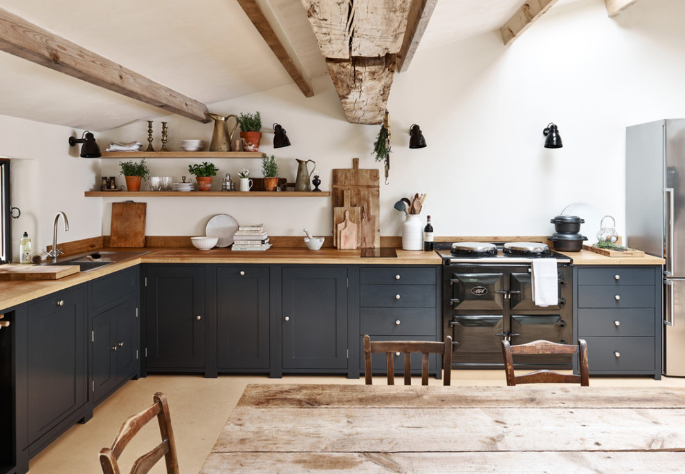 Immagine di una cucina country di medie dimensioni con ante con riquadro incassato, ante blu, top in legno, nessuna isola e pavimento beige