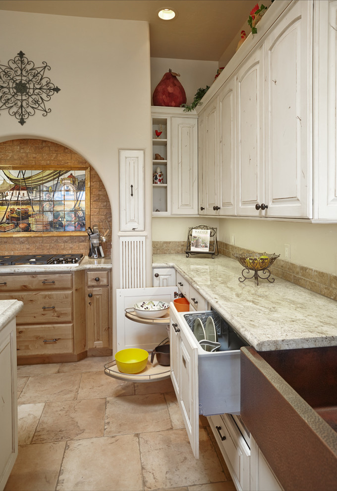 Bild på ett stort lantligt kök, med en rustik diskho, luckor med upphöjd panel, skåp i slitet trä, granitbänkskiva, beige stänkskydd, integrerade vitvaror, travertin golv, en köksö och beiget golv