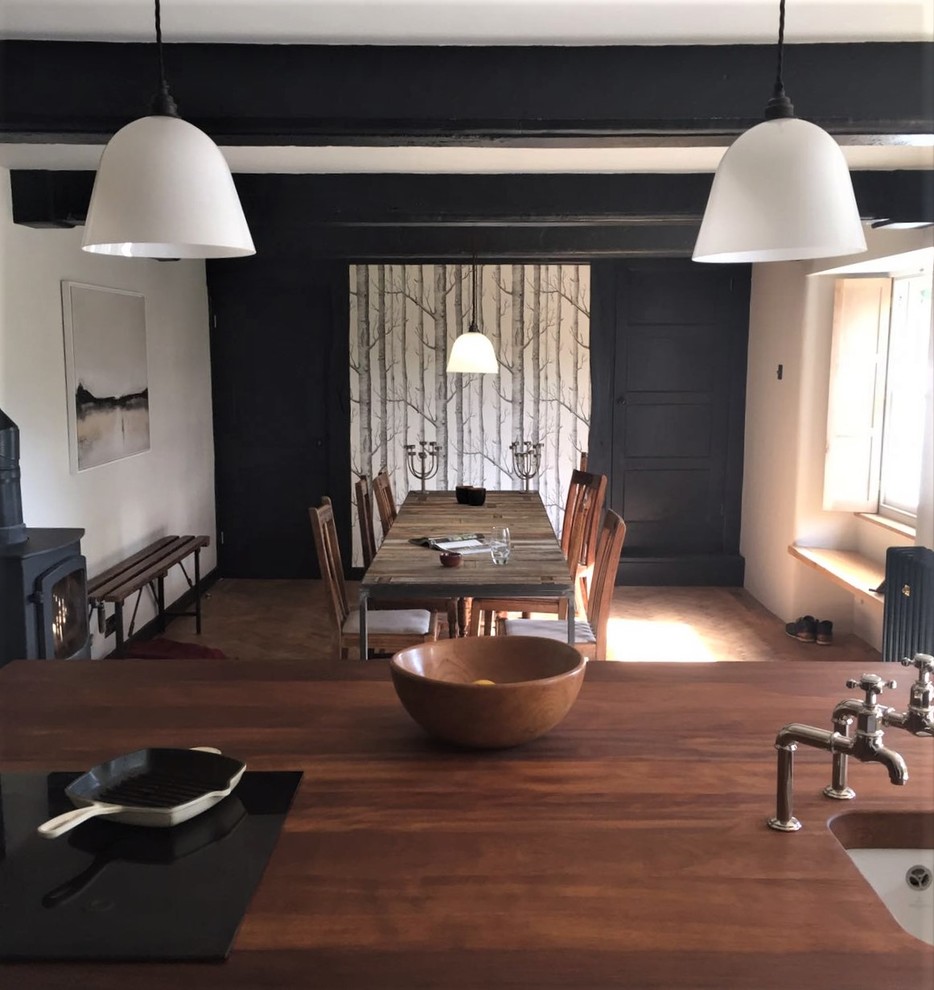 Cette image montre une grande salle à manger ouverte sur la cuisine rustique avec un sol en bois brun.