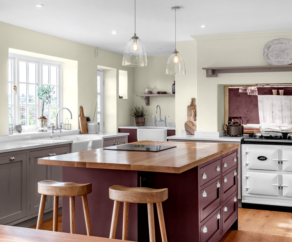 Inspiration for a classic kitchen in Other with a belfast sink, shaker cabinets, beige cabinets, white appliances, medium hardwood flooring, an island, brown floors and white worktops.