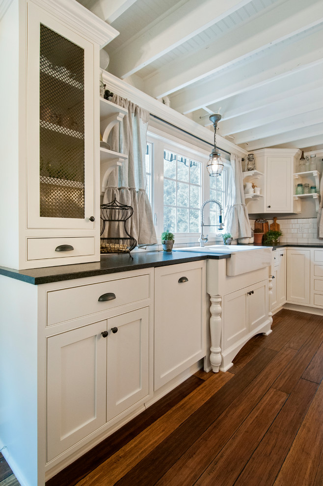 Eat-in kitchen - cottage u-shaped medium tone wood floor and brown floor eat-in kitchen idea in Seattle with a farmhouse sink, shaker cabinets, white cabinets, quartz countertops, white backsplash, subway tile backsplash, stainless steel appliances and an island