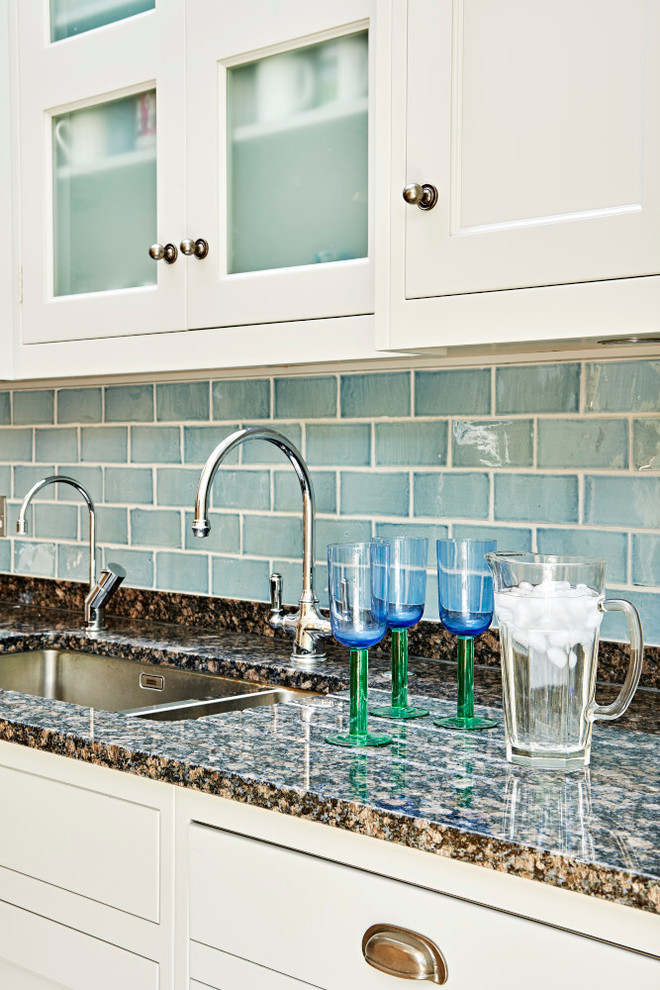 Example of a mid-sized country eat-in kitchen design in London with a farmhouse sink, shaker cabinets, granite countertops, blue backsplash, ceramic backsplash, stainless steel appliances and an island