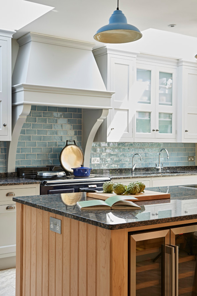 Inredning av ett lantligt mellanstort kök, med en rustik diskho, skåp i shakerstil, granitbänkskiva, blått stänkskydd, stänkskydd i keramik, rostfria vitvaror, en köksö och vita skåp