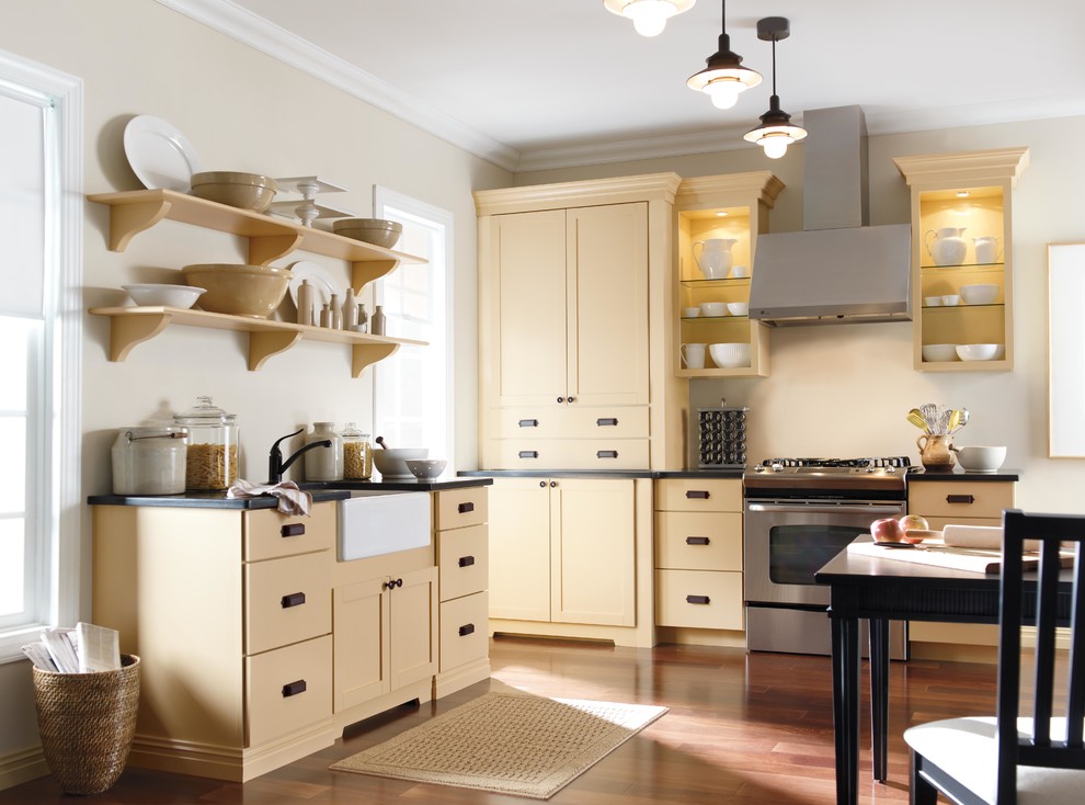ニューヨークにある中くらいなカントリー風のおしゃれなキッチン (シェーカースタイル扉のキャビネット、黄色いキャビネット、シルバーの調理設備、無垢フローリング) の写真