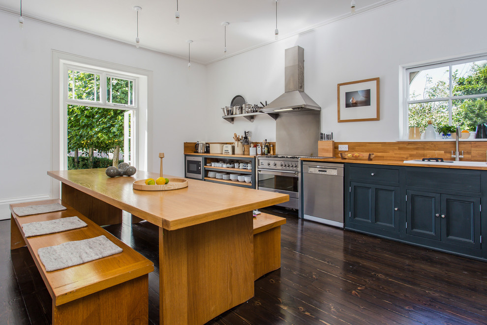 Inspiration for a traditional kitchen/diner in Sussex with recessed-panel cabinets, brown cabinets, wood worktops, stainless steel appliances and dark hardwood flooring.