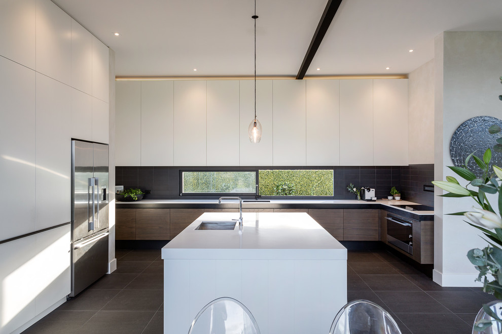 Trendy u-shaped kitchen photo in Auckland with an undermount sink, flat-panel cabinets, white cabinets, black backsplash, stainless steel appliances and an island