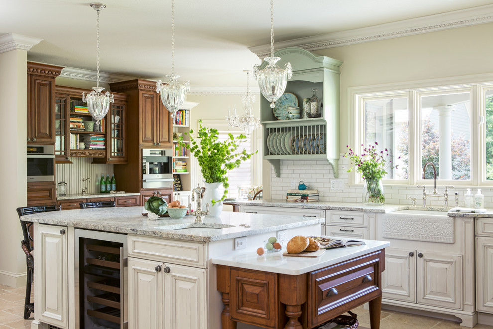 Kitchen - traditional l-shaped porcelain tile kitchen idea in Other with a farmhouse sink, raised-panel cabinets, white cabinets, granite countertops, white backsplash, subway tile backsplash, stainless steel appliances and an island