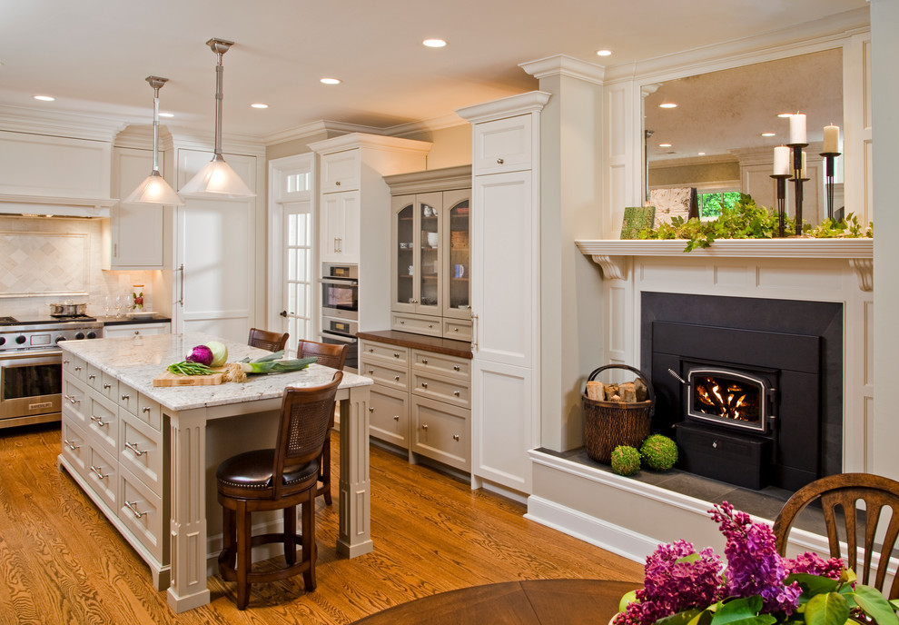 Example of a large classic u-shaped medium tone wood floor eat-in kitchen design in Philadelphia with recessed-panel cabinets, white cabinets, marble countertops, white backsplash, ceramic backsplash, stainless steel appliances and an island