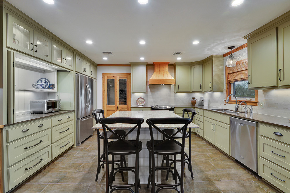 This is an example of a classic u-shaped kitchen/diner in New Orleans with a submerged sink, beaded cabinets, green cabinets, beige splashback, stainless steel appliances and an island.