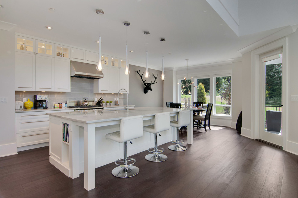 Open concept kitchen - transitional open concept kitchen idea in Vancouver with an island, shaker cabinets, white cabinets, granite countertops, gray backsplash, glass tile backsplash, stainless steel appliances and an undermount sink