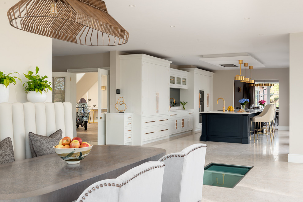 Inspiration for a large contemporary limestone floor and white floor open concept kitchen remodel in London with an integrated sink, shaker cabinets, white cabinets, solid surface countertops, brown backsplash, glass sheet backsplash, colored appliances, an island and white countertops