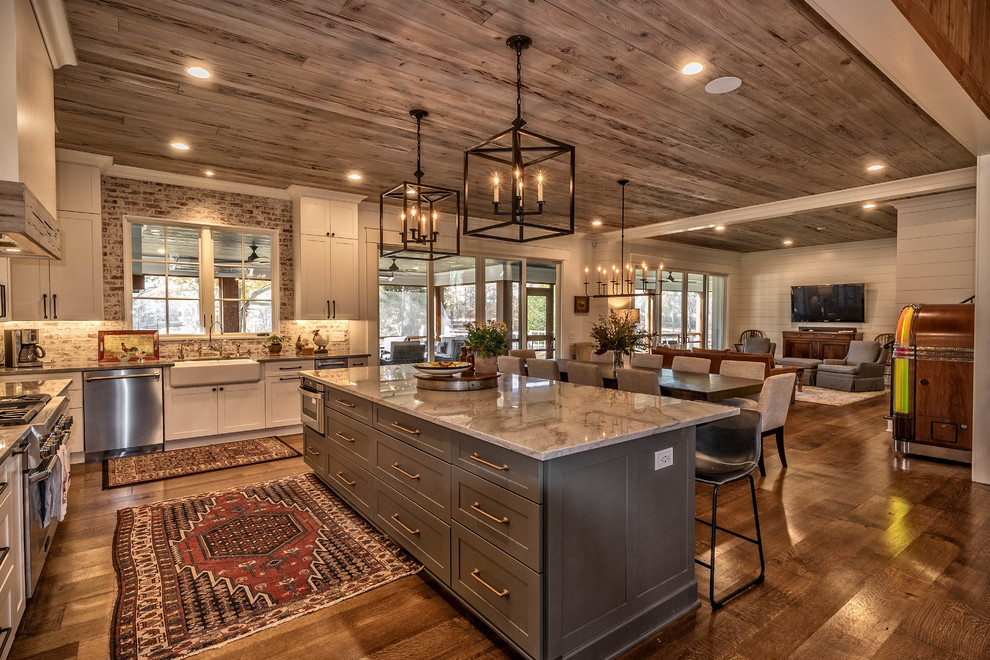 Kitchen - rustic l-shaped dark wood floor and brown floor kitchen idea in Other with a farmhouse sink, shaker cabinets, white cabinets, brick backsplash, stainless steel appliances, an island and gray countertops