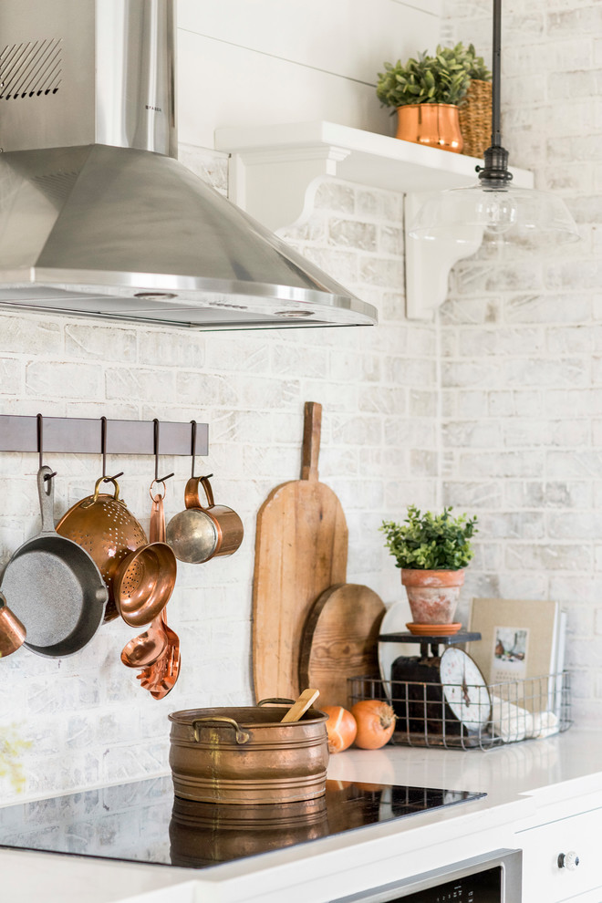 Country u-shaped light wood floor and beige floor eat-in kitchen photo in Minneapolis with a farmhouse sink, white cabinets, white backsplash, brick backsplash, stainless steel appliances, an island and white countertops