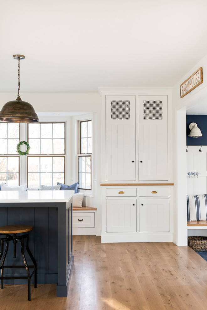 Exempel på ett lantligt vit vitt kök och matrum, med en rustik diskho, vita skåp, stänkskydd i tegel, rostfria vitvaror, ljust trägolv, en köksö och beiget golv