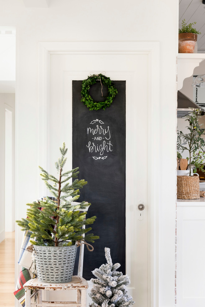 Example of a farmhouse u-shaped light wood floor and beige floor eat-in kitchen design in Minneapolis with a farmhouse sink, white cabinets, white backsplash, brick backsplash, stainless steel appliances, an island and white countertops