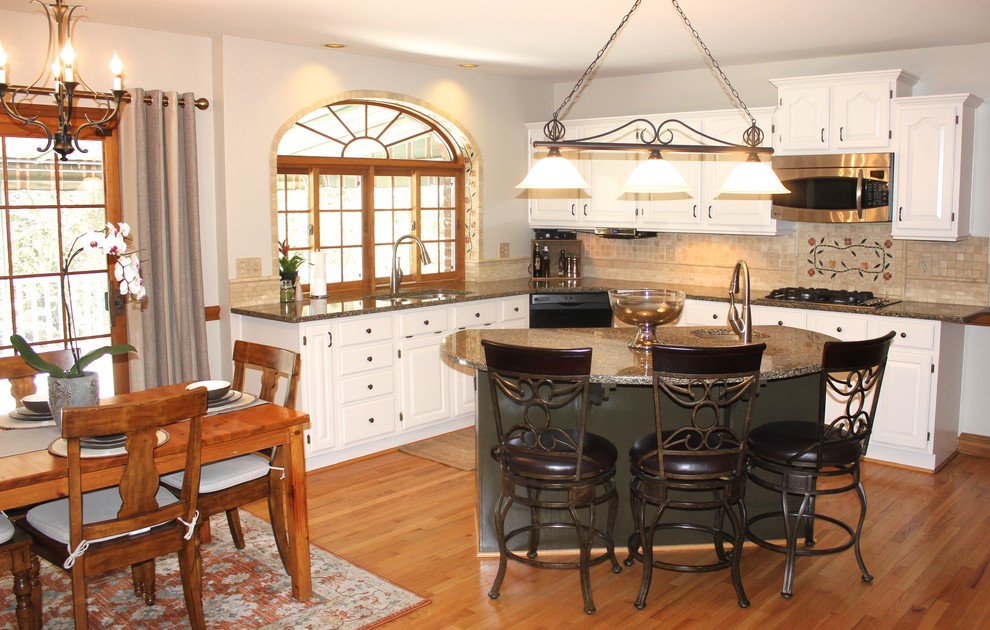 Eat-in kitchen - mid-sized rustic l-shaped medium tone wood floor eat-in kitchen idea in Nashville with a double-bowl sink, raised-panel cabinets, white cabinets, quartz countertops, beige backsplash, stone tile backsplash, stainless steel appliances and an island