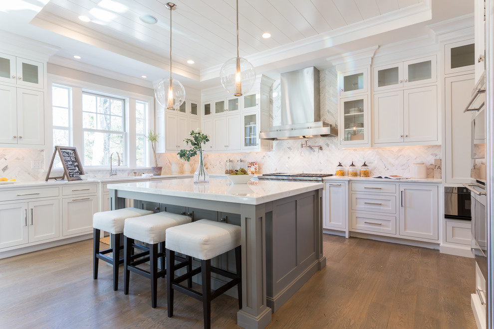 Large trendy u-shaped medium tone wood floor and brown floor eat-in kitchen photo in New York with a farmhouse sink, shaker cabinets, white cabinets, marble countertops, multicolored backsplash, stone tile backsplash, stainless steel appliances and an island
