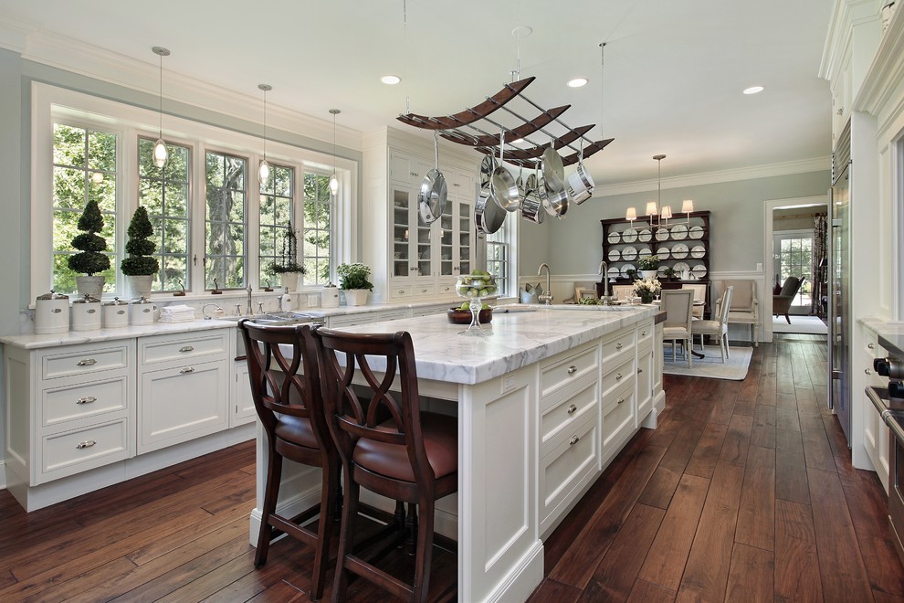 Inspiration for a large rustic galley dark wood floor eat-in kitchen remodel in Los Angeles with a farmhouse sink, shaker cabinets, white cabinets, marble countertops, white backsplash, stone tile backsplash, stainless steel appliances and an island