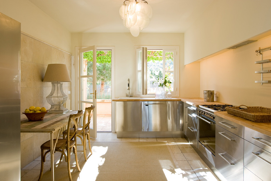 Immagine di una cucina mediterranea di medie dimensioni con ante lisce, ante in acciaio inossidabile, top in legno, paraspruzzi beige, elettrodomestici in acciaio inossidabile e nessuna isola